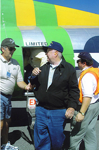 Elderly man standing in a group outdoors in front of an Air Force aircraft on a sunny day